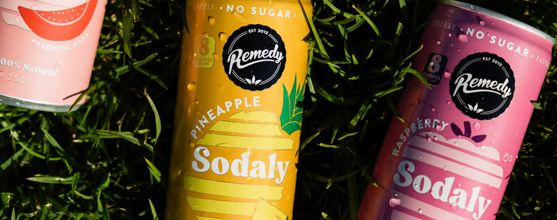 Picture of 3 cans lying on the grass: Sodaly Guava, Sodaly Pineapple and Sodaly Raspberry