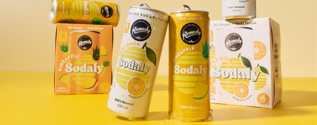 One can of Yuzu Sodaly and one can of Pineapple Sodaly leaning on each other